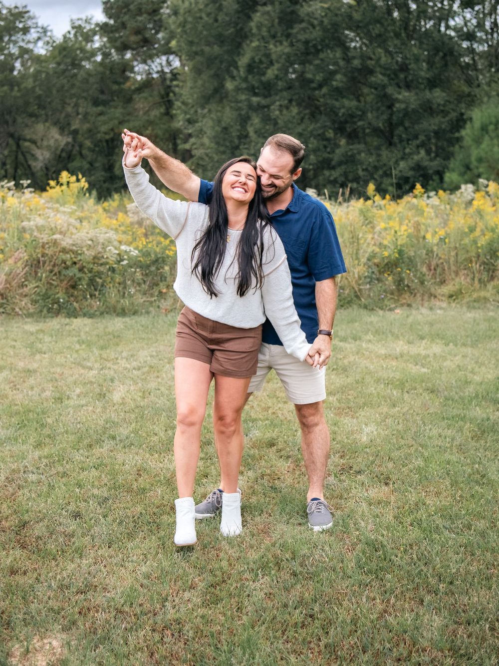 Couple's feet shown in a playful outdoor photoshoot with grass and yellow flowers in the background.
