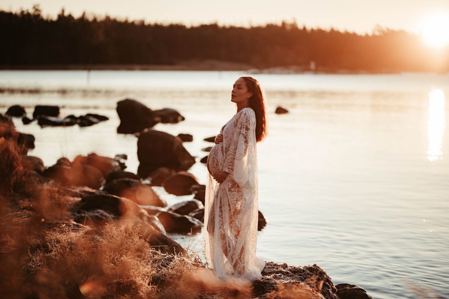 Gravid kvinna i vid havet i solnedången en kall vinter morgon