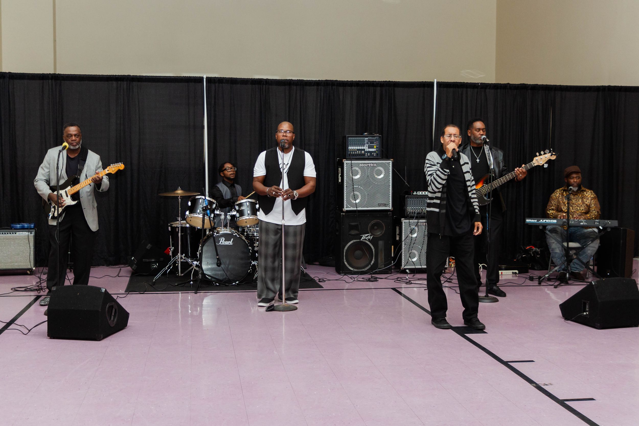 A live band performs on stage with guitars and musical equipment at an event.