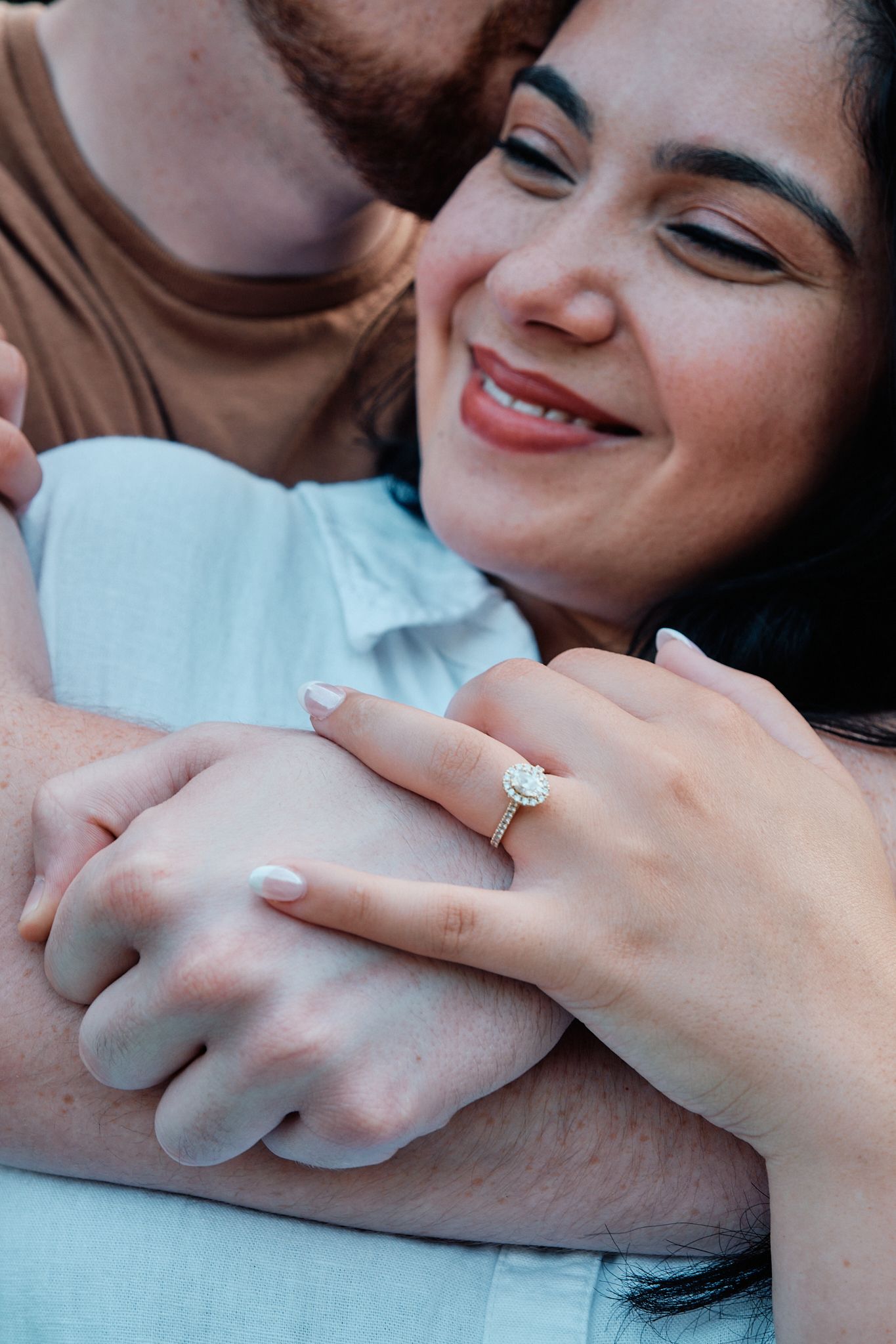 Close-up shot of an engagement ring on a hand during an intimate romantic moment in natural light.