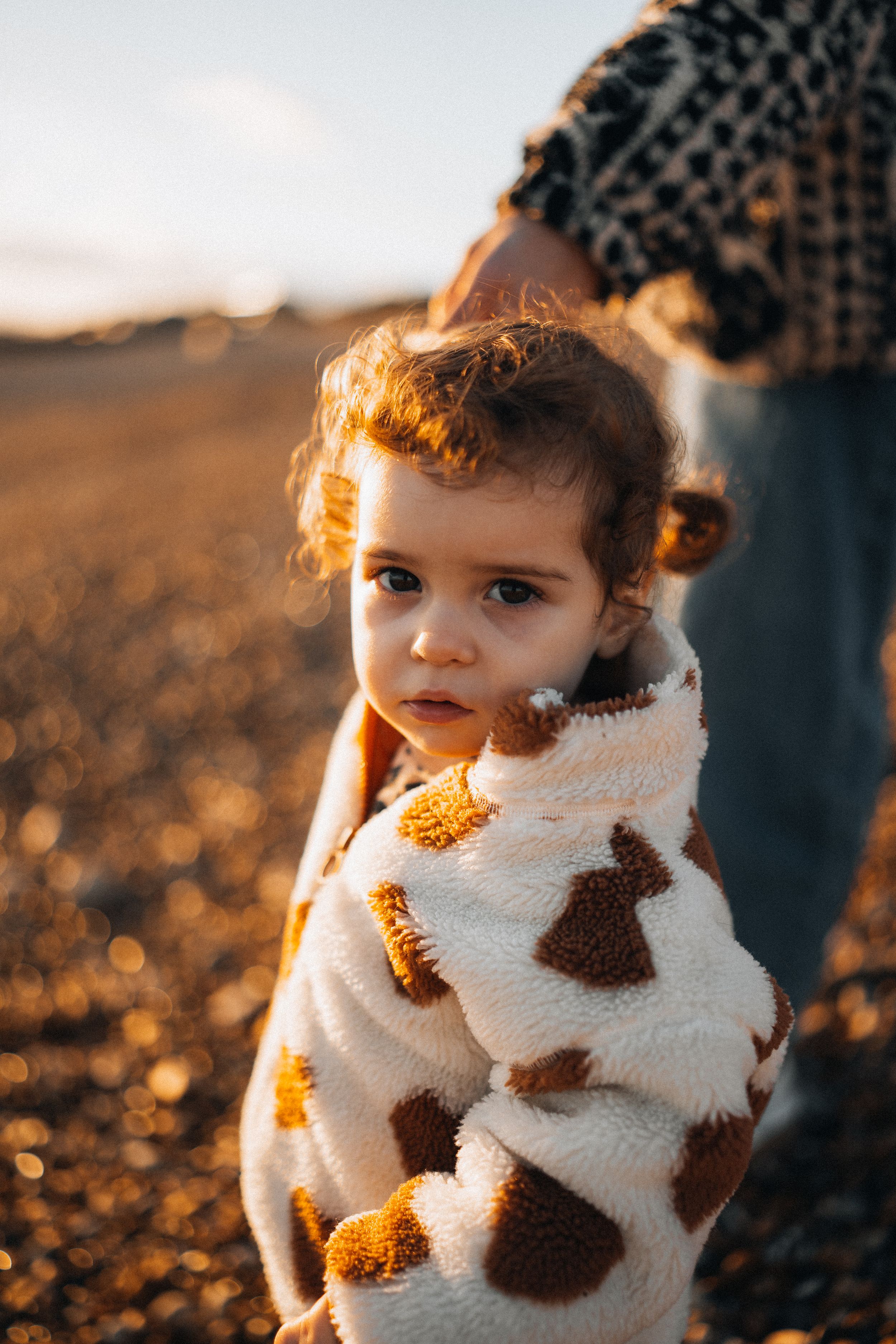 Child wearing a cozy patterned sweater in golden sunset light.