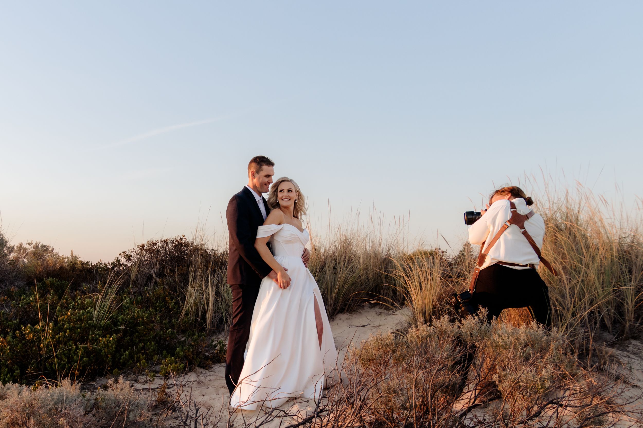 Professional photographer with camera captures shots in a lush garden setting with wooden fence.