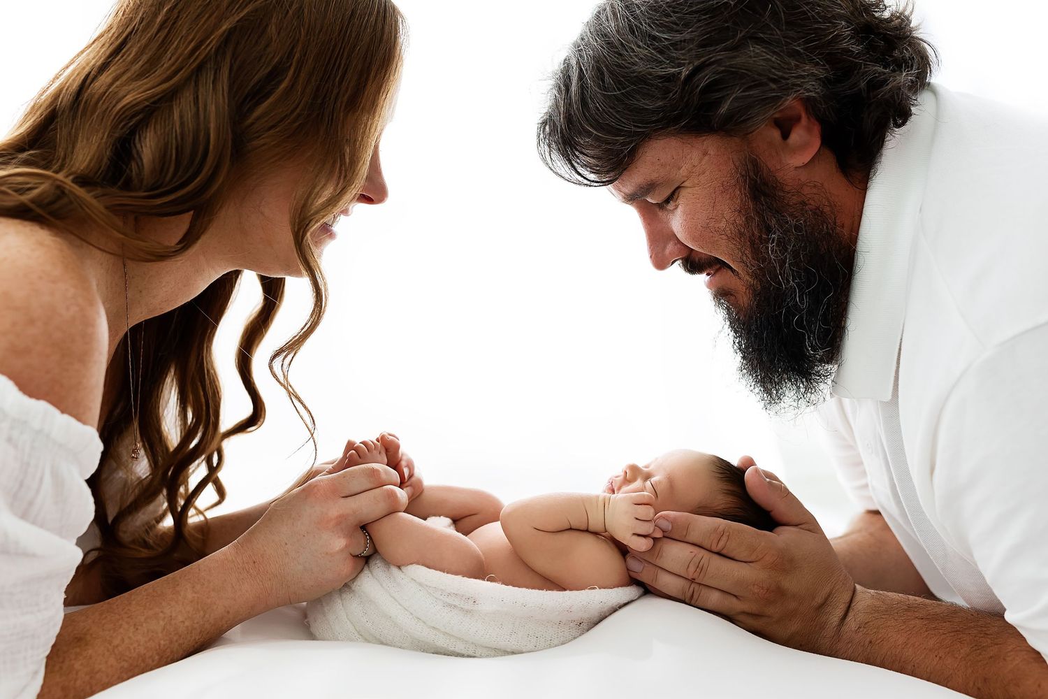 Three hands lovingly embrace a pregnant belly in an intimate maternity photo.