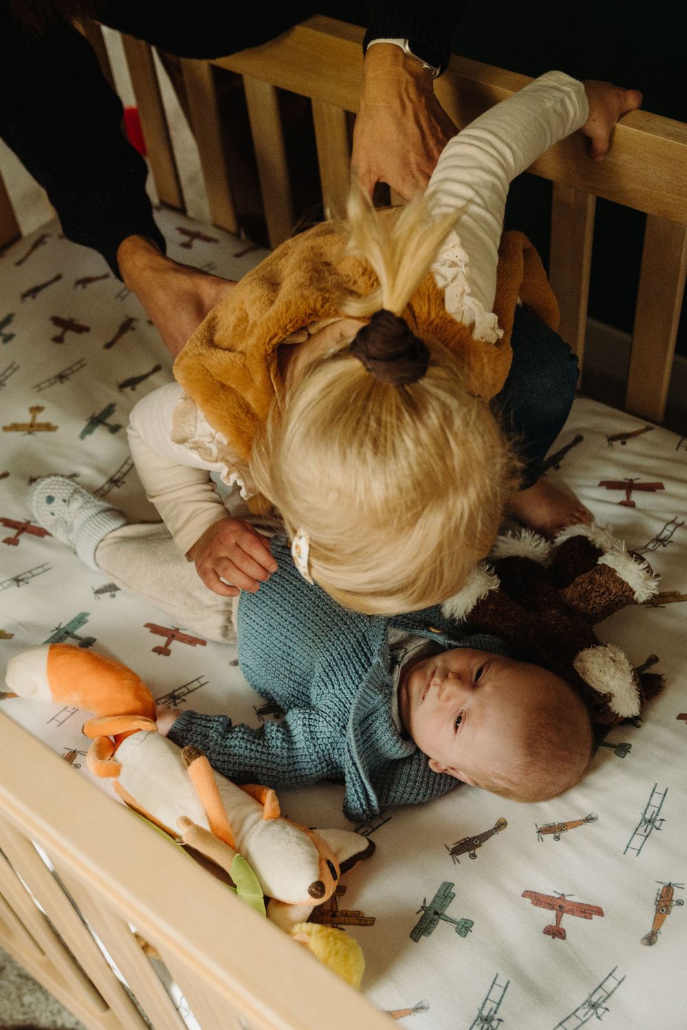 A tender moment shared over a crib with airplane-patterned bedding.