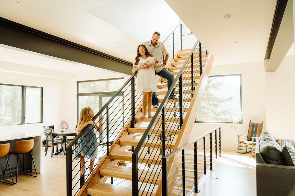 A family poses on modern wooden stairs in their contemporary mountain home.