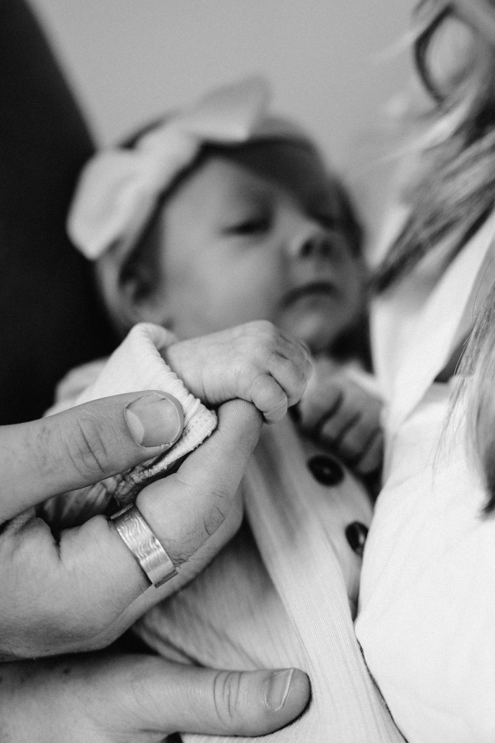 Black and white close-up of a tiny baby hand holding an adult's finger.