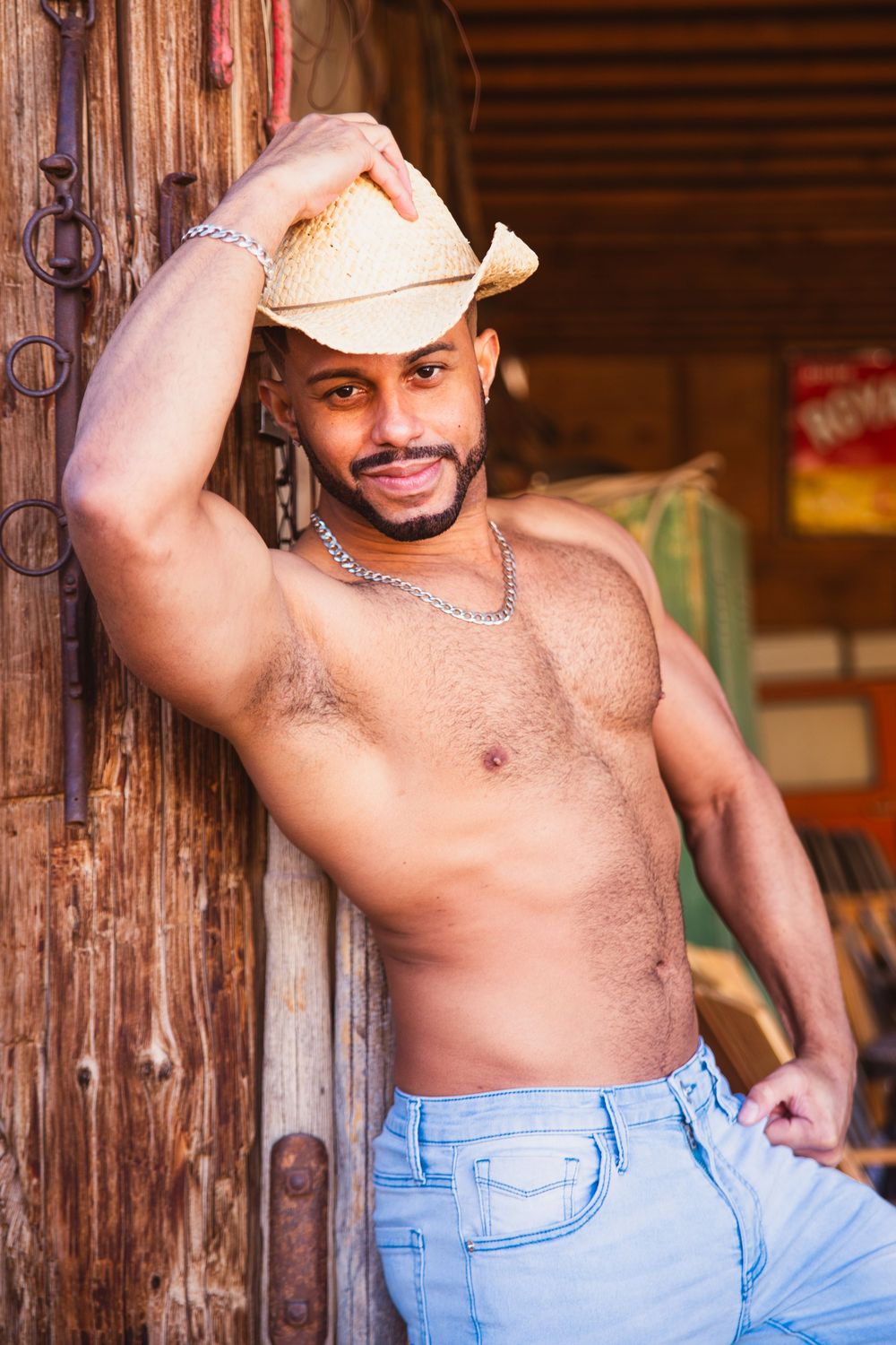 Shirtless man in beige hat and jeans poses against rustic wooden background. Cowboy style Las Vegas in Nelson Ghost Town
