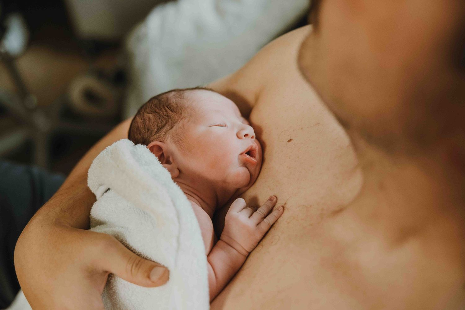 Newborn baby resting on parent's chest during skin-to-skin contact after birth.
