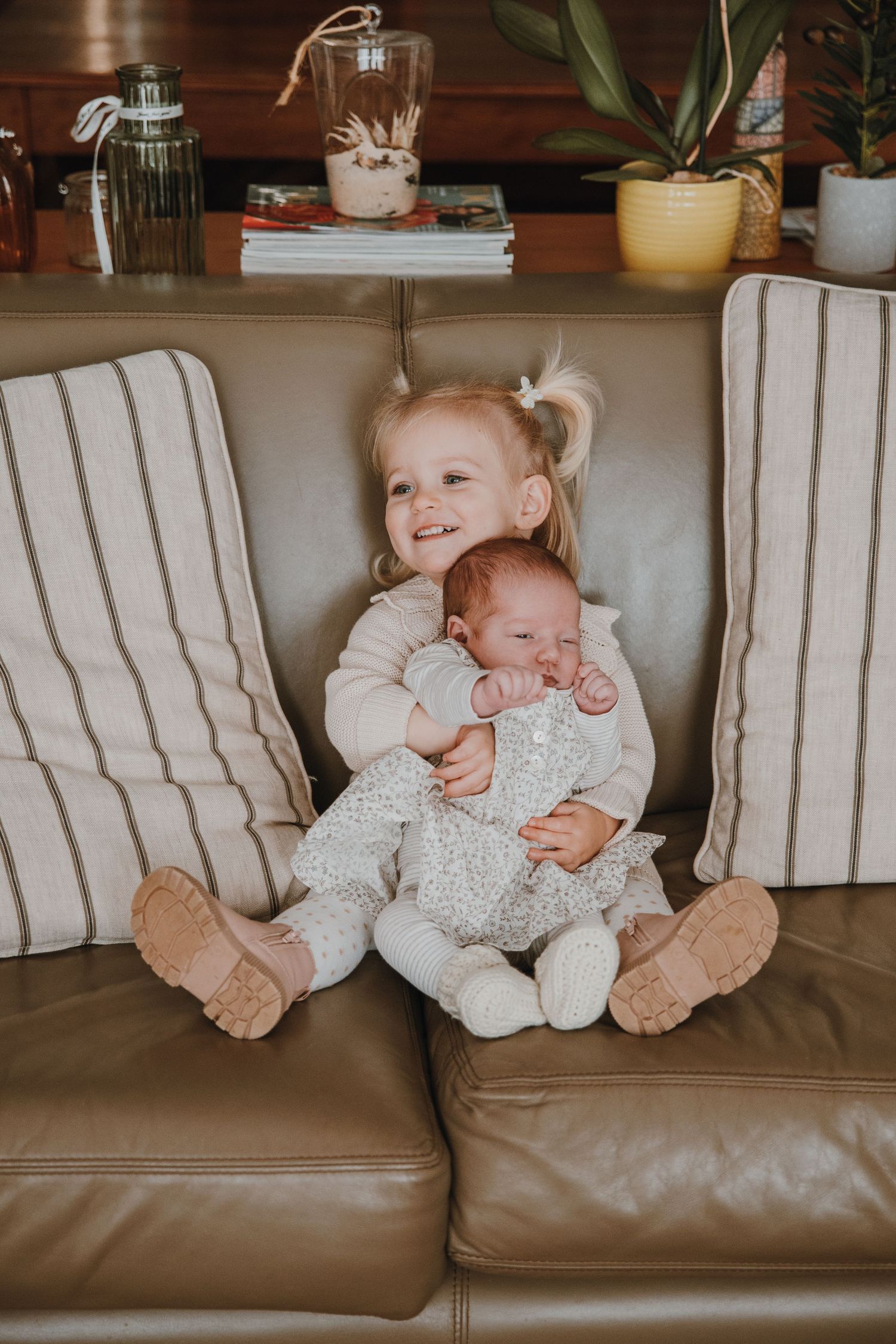 Two siblings share a sweet moment together on a striped leather couch.