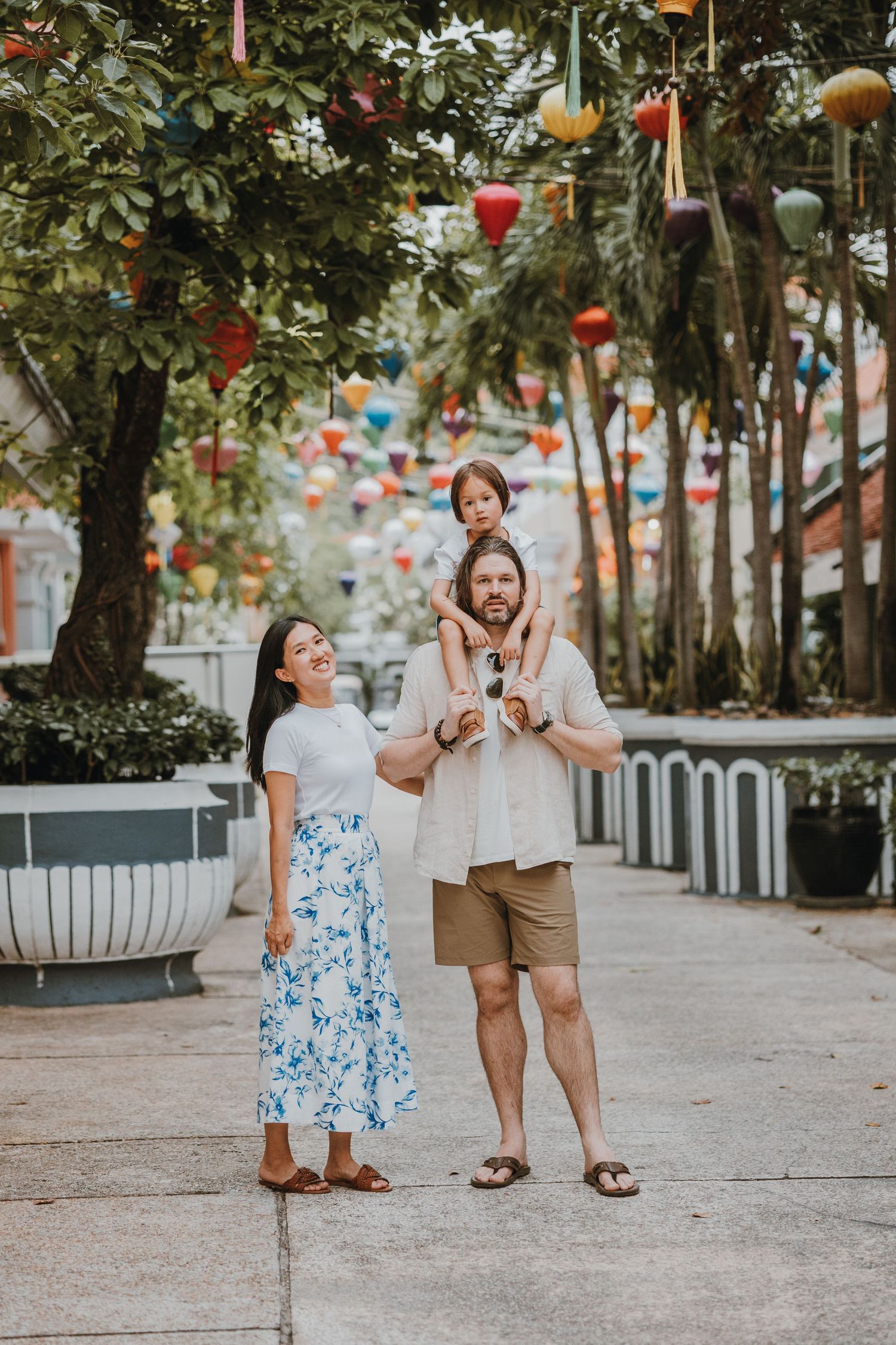 Family enjoying a festive outdoor walkway decorated with colorful hanging lanterns and string lights.