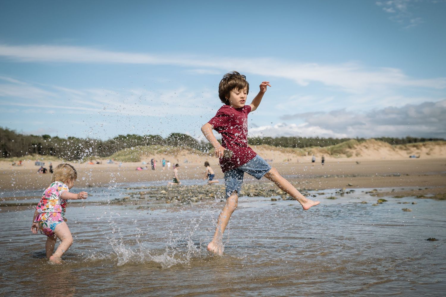 People splashing and jumping in ocean waves at a sunny beach.