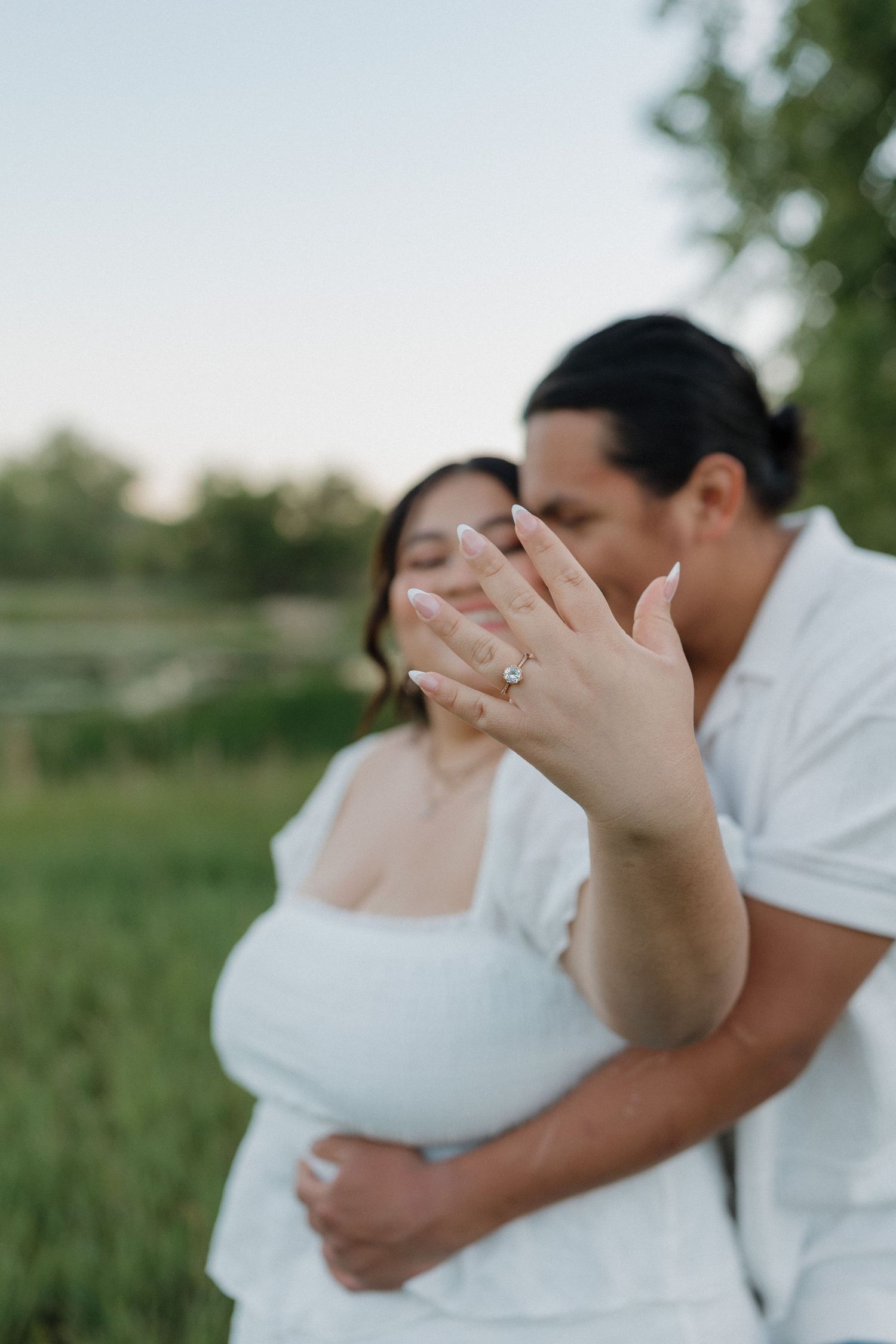 Two people share an intimate moment in a home setting with green plants and white decor in the background.