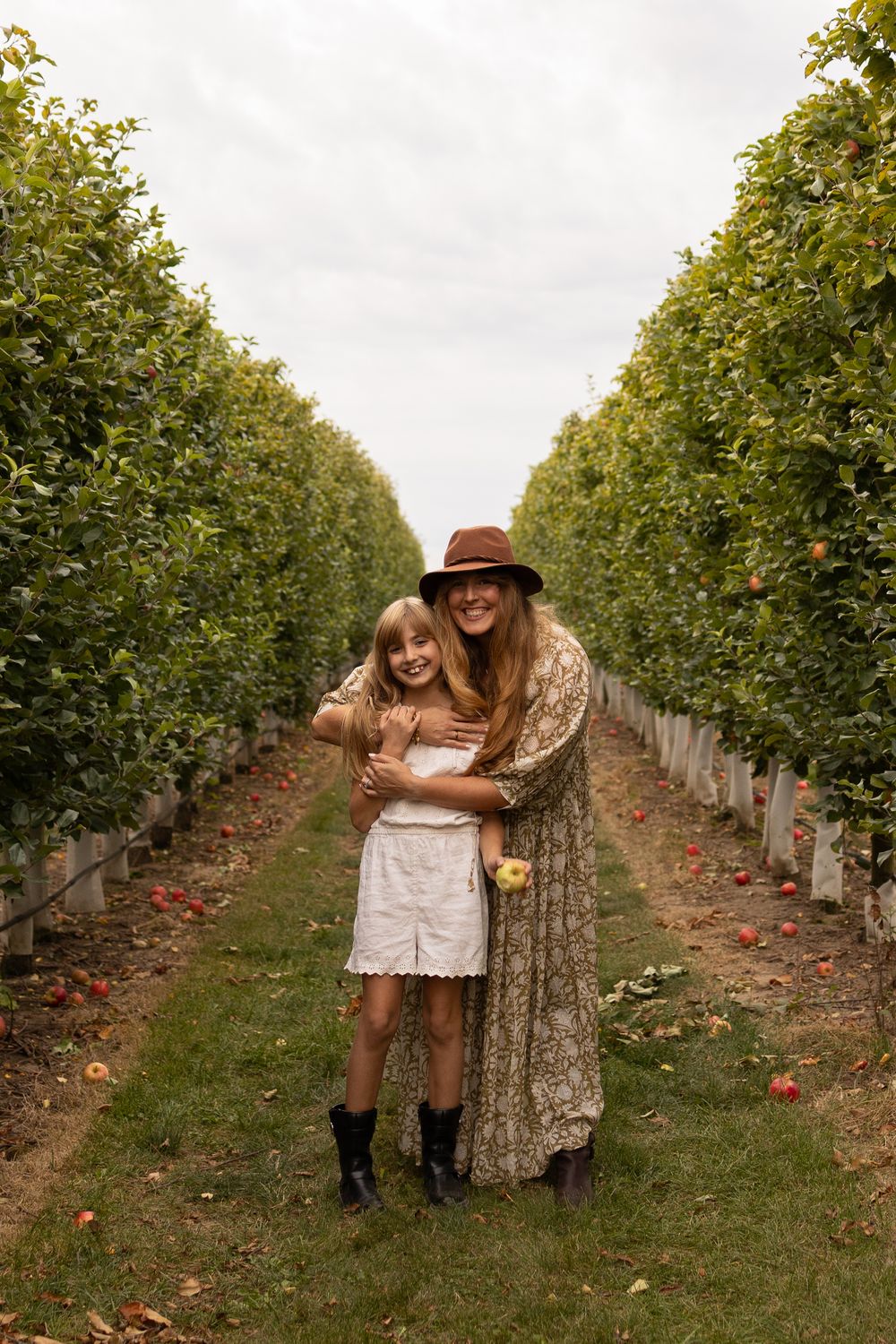 People share joyful moments while standing between rows of fruit trees in a lush orchard in Elmira Ontario