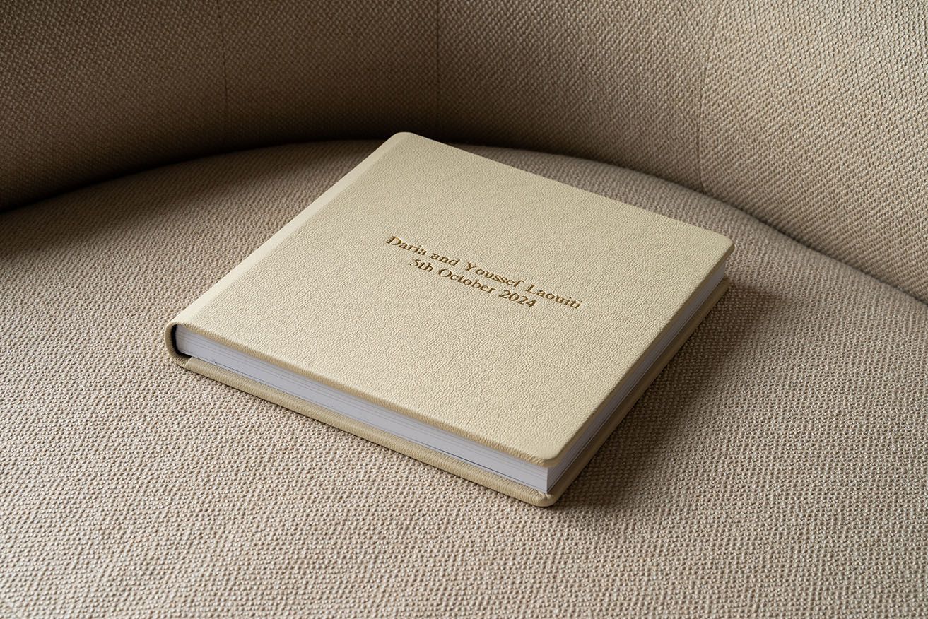 Minimalist beige photo album with delicate text lying on neutral upholstered seating.