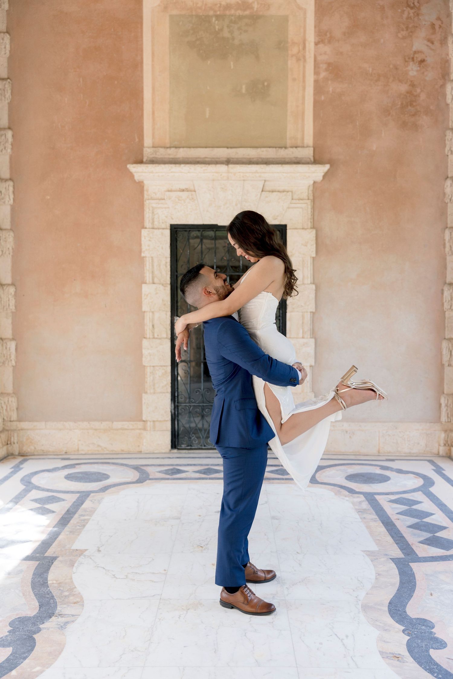 Joyful wedding couple dancing and twirling in white formal attire.