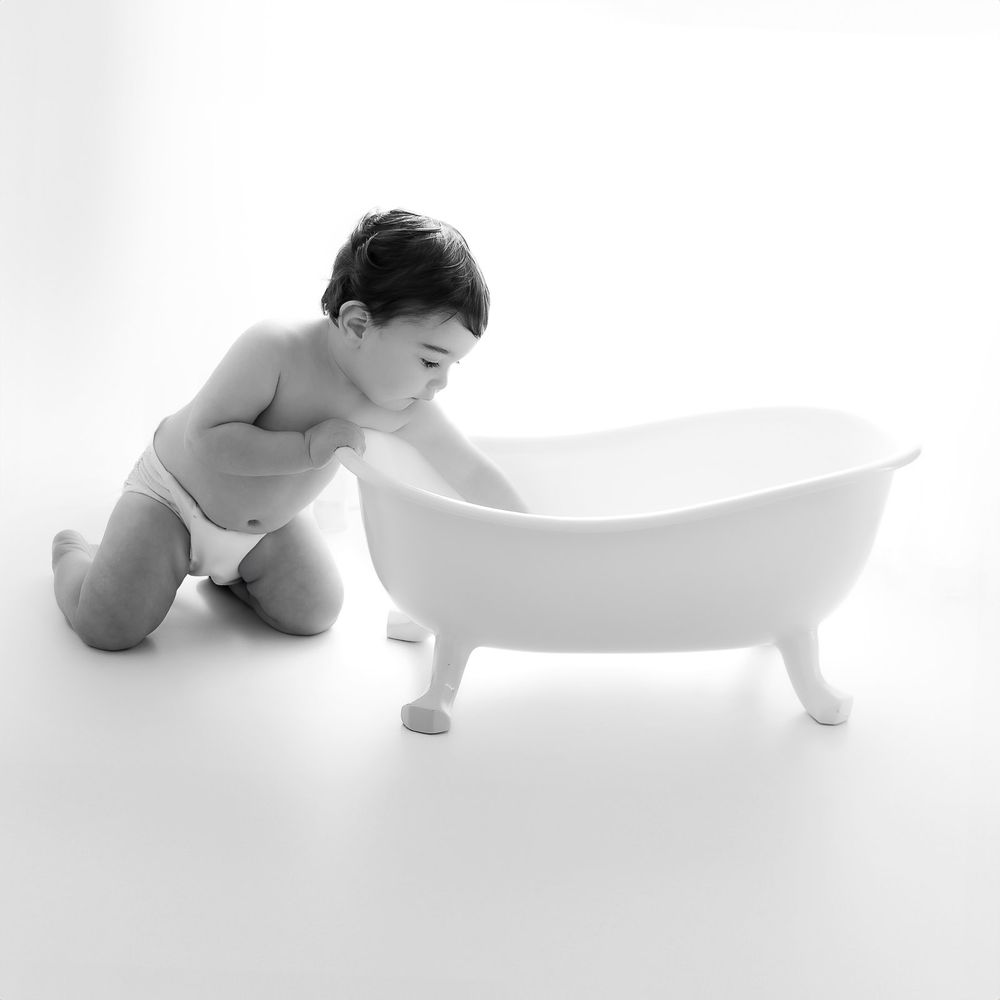 Black and white artistic photos of baby in minimalist bathtub series showing different angles and poses.