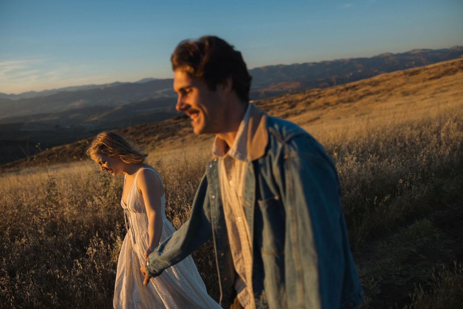 Engagement photos of a couple holding hands and walking through the grassy hills of Simi Valley, California