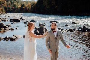 Mariés découvrant leurs tenues lors d’un first look au bord d’une rivière, moment capturé en nature au Québec.