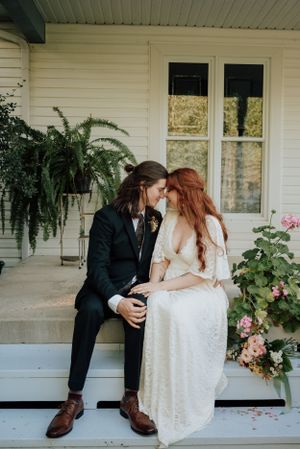 Mariés assis sur le perron d’une maison blanche, instant romantique au style rustique au Québec.
