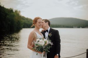 Couple de mariés souriants lors d’une séance photo au bord de l’eau dans un décor naturel typique du Québec.