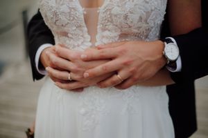 Photo intime de mariage avec détail des mains et montres élégantes des mariés.