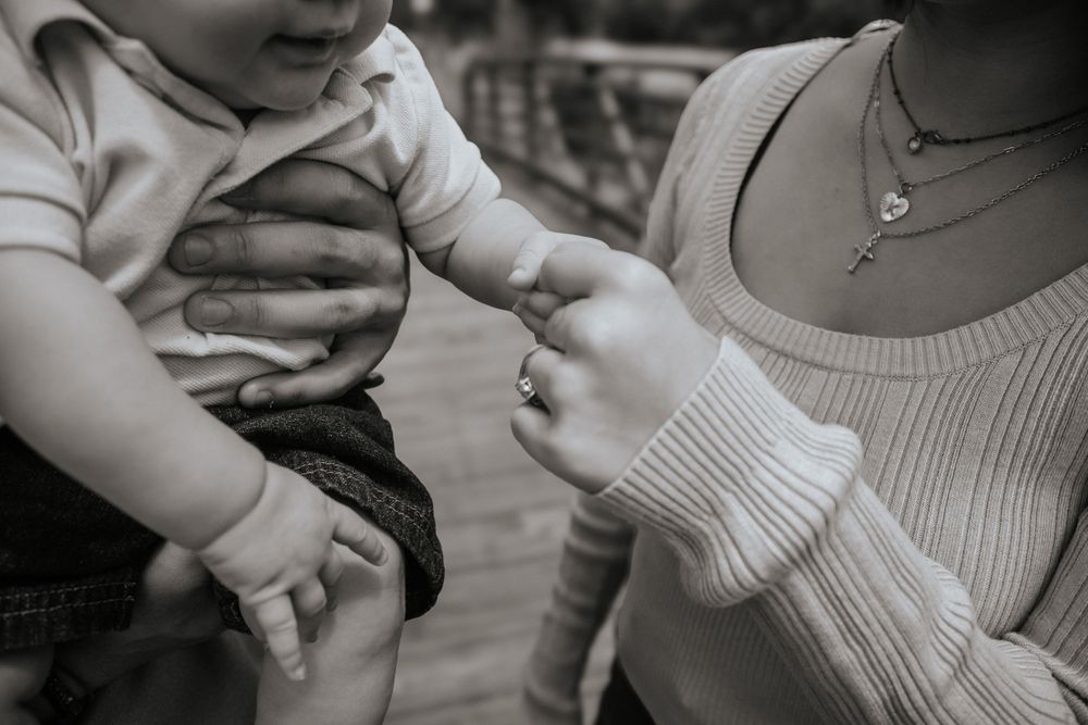 Close-up detail shot of hands holding a baby wearing soft clothing.