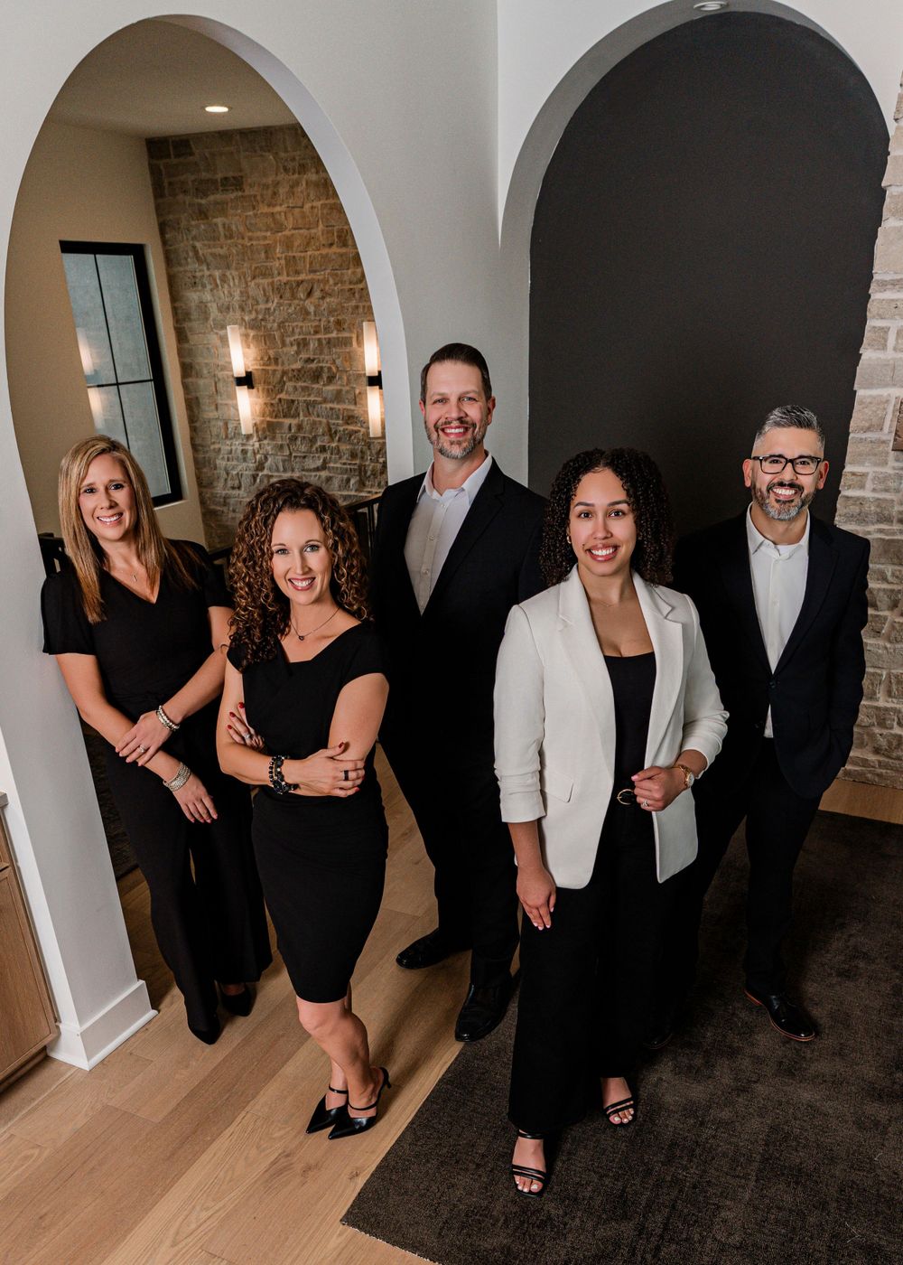 Group of people in black and white formal attire posing for a sequence of photos in a modern interior space.