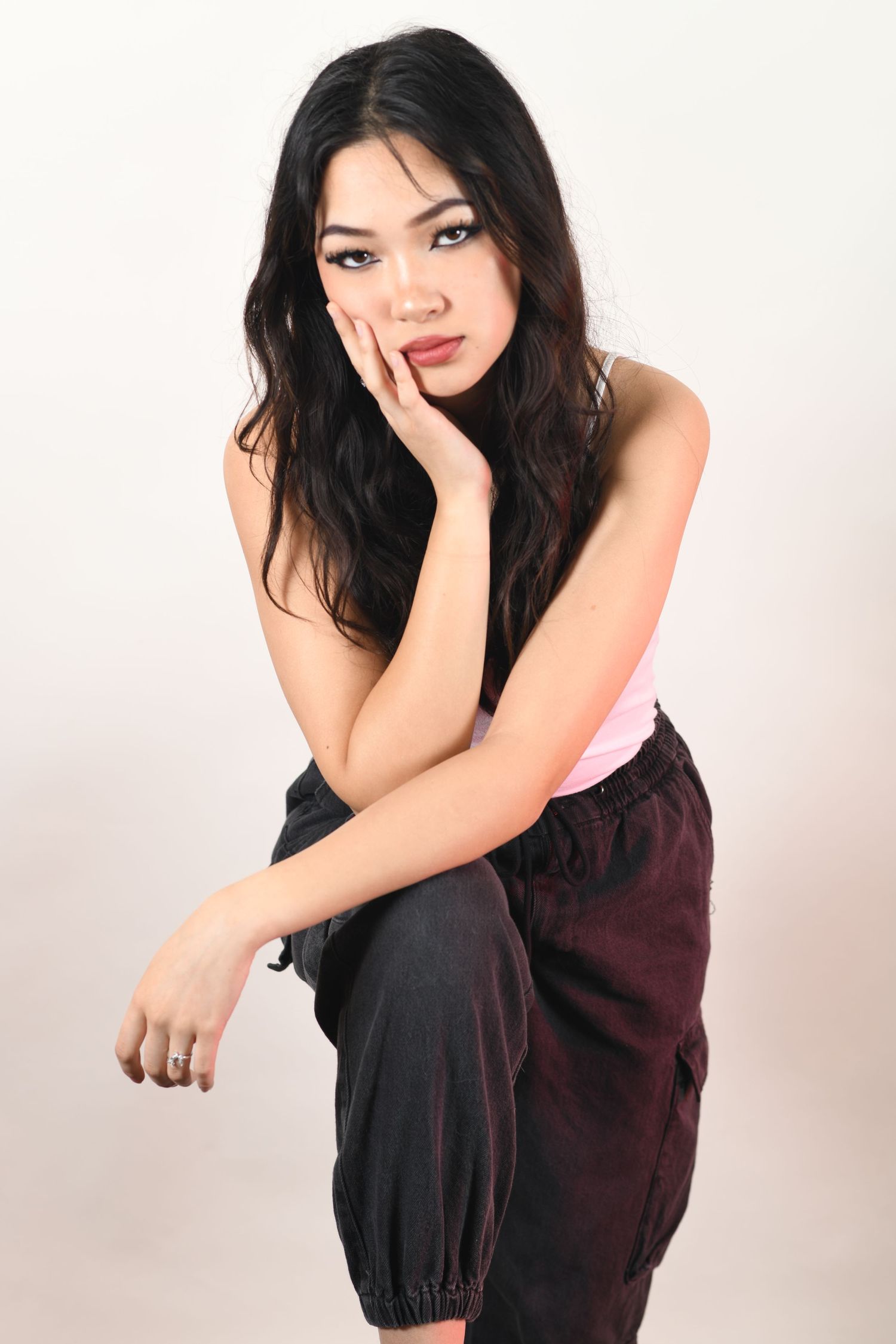 Portrait of person in casual black attire posing against white studio background.
