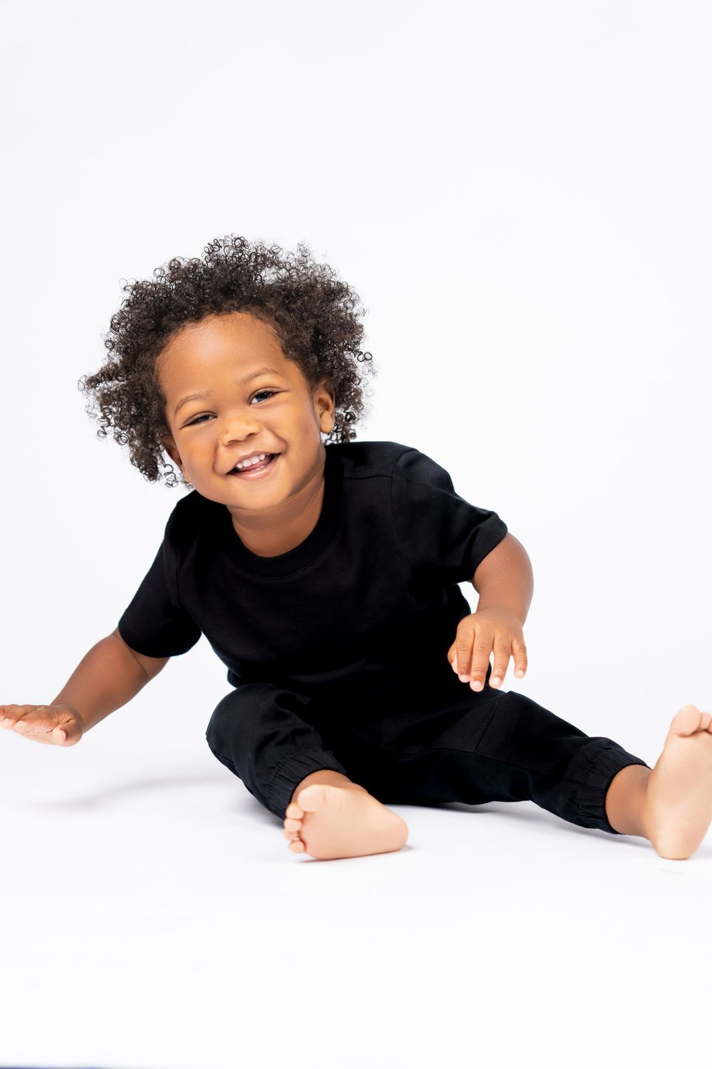 A child in a black shirt lying down on a white background in four playful poses.