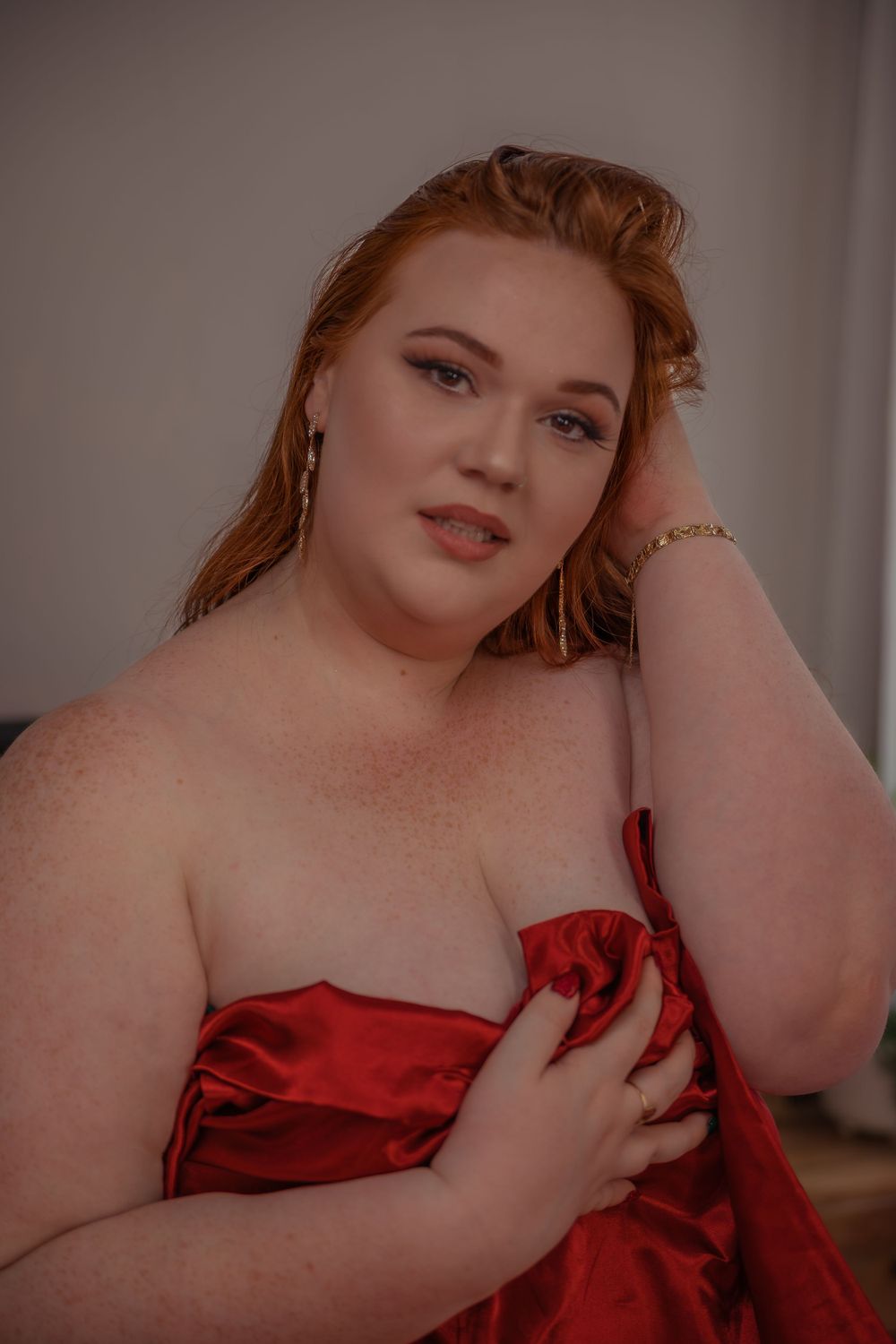 Boudoir portrait with red silk fabric and intimate studio lighting creating a moody romantic atmosphere.