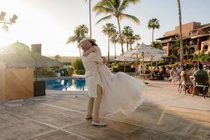 Bride and groom kissing under sunset sky in Cabo San Lucas
