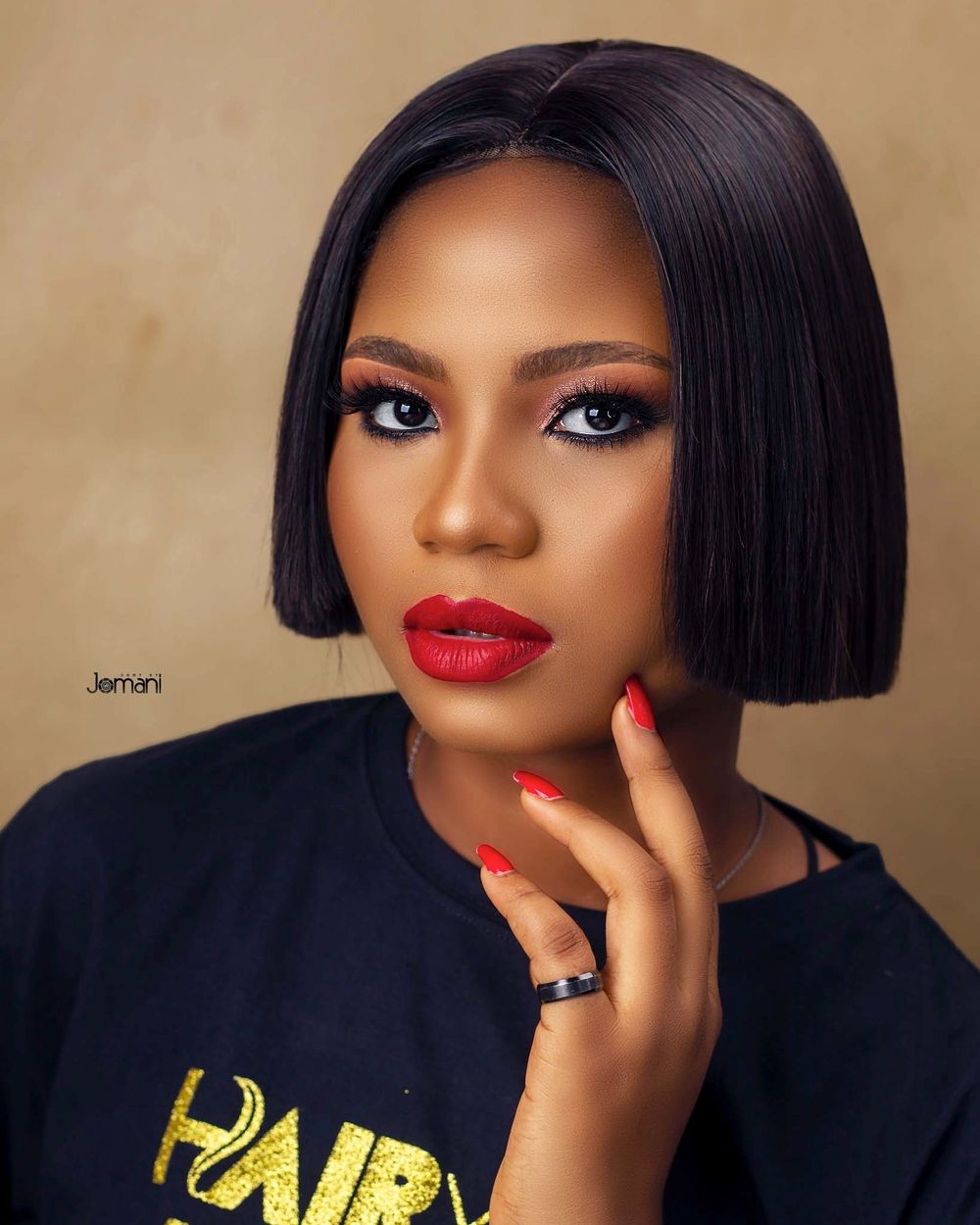 Woman with a sleek black bob hairstyle wearing red lipstick and matching nails.
