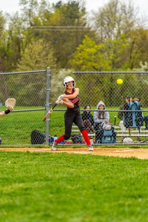 Banshees softball team swinging at a pitch