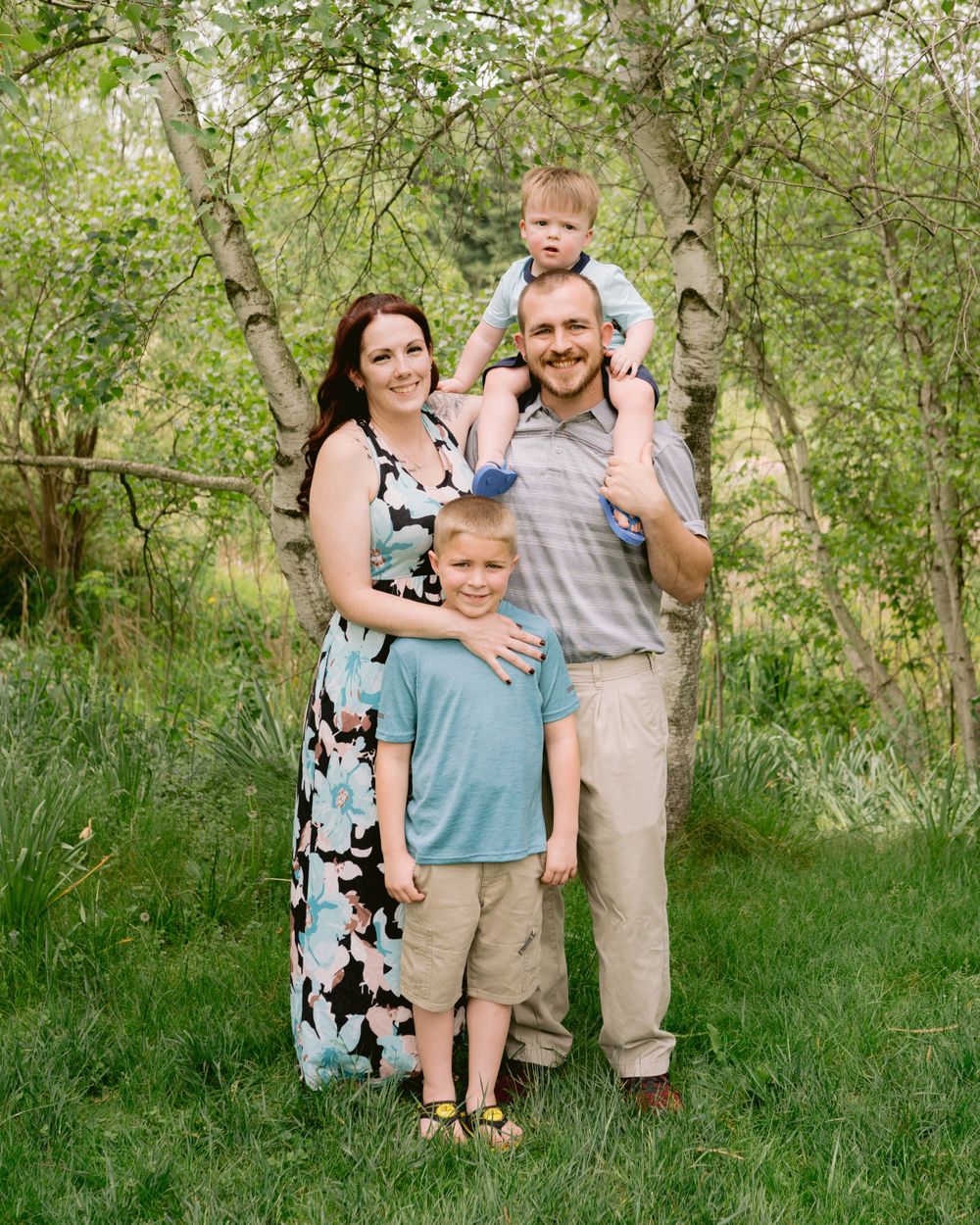 A family of four poses together outdoors among spring blossoms.