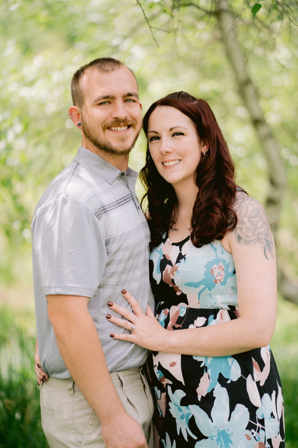A couple in casual attire shares a romantic moment among spring blossoms.