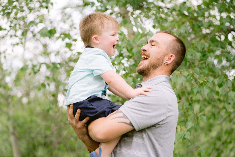 A joyful moment shared between two people playing outdoors among green foliage.