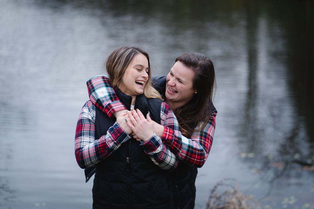 Close up of people embracing by water during outdoor photo session.