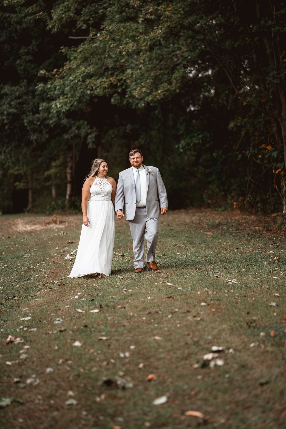 A couple takes a romantic stroll on a fall day in their wedding attire.