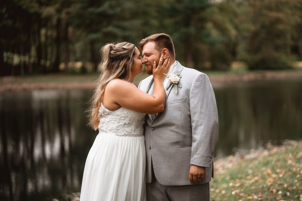 An intimate wedding celebration beside a tranquil lake surrounded by autumn trees.