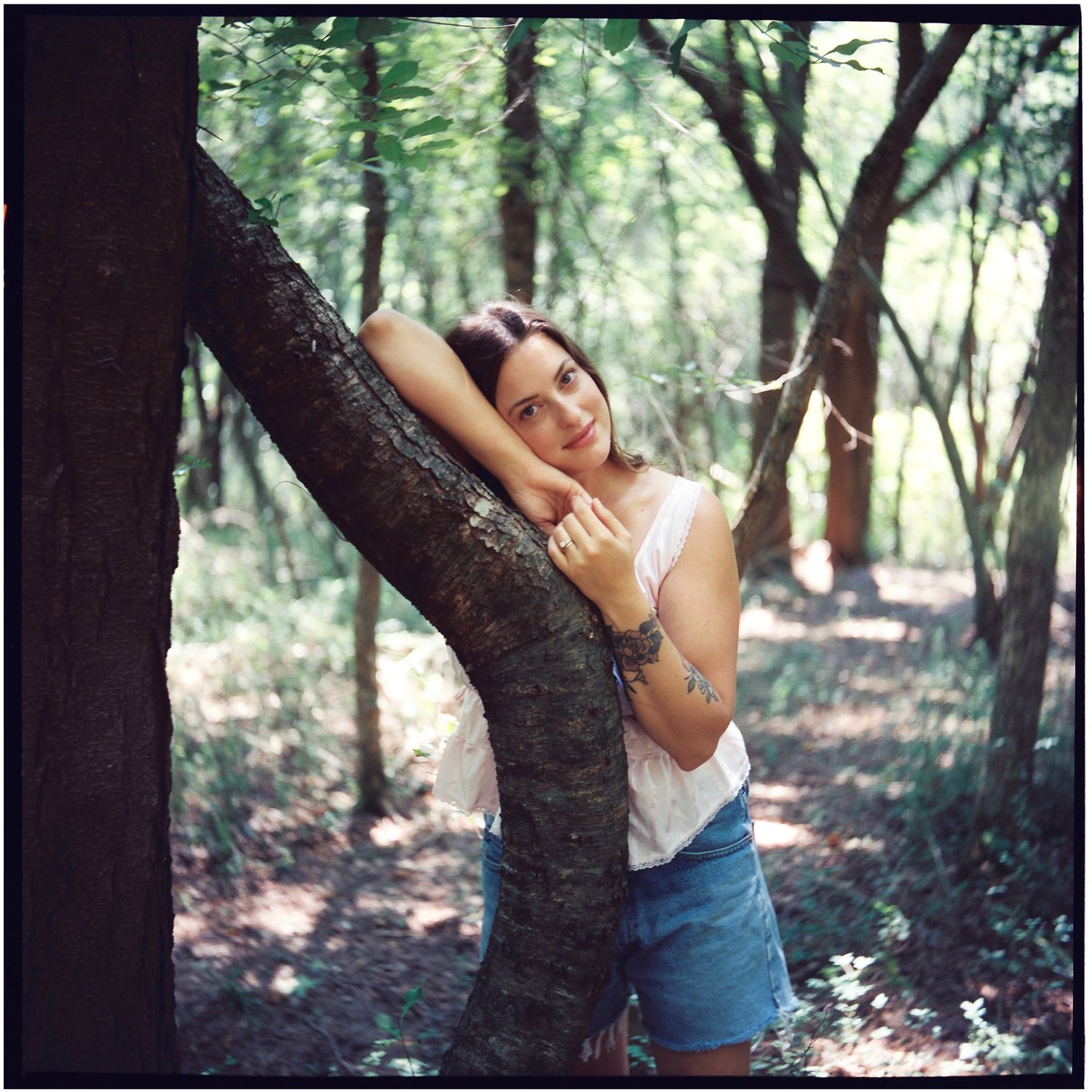 Artistic portrait in nature showing someone embracing a tree trunk.