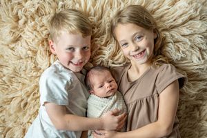 Children lying on a cream colored shag carpet or rug with natural light creating a warm, cozy atmosphere.