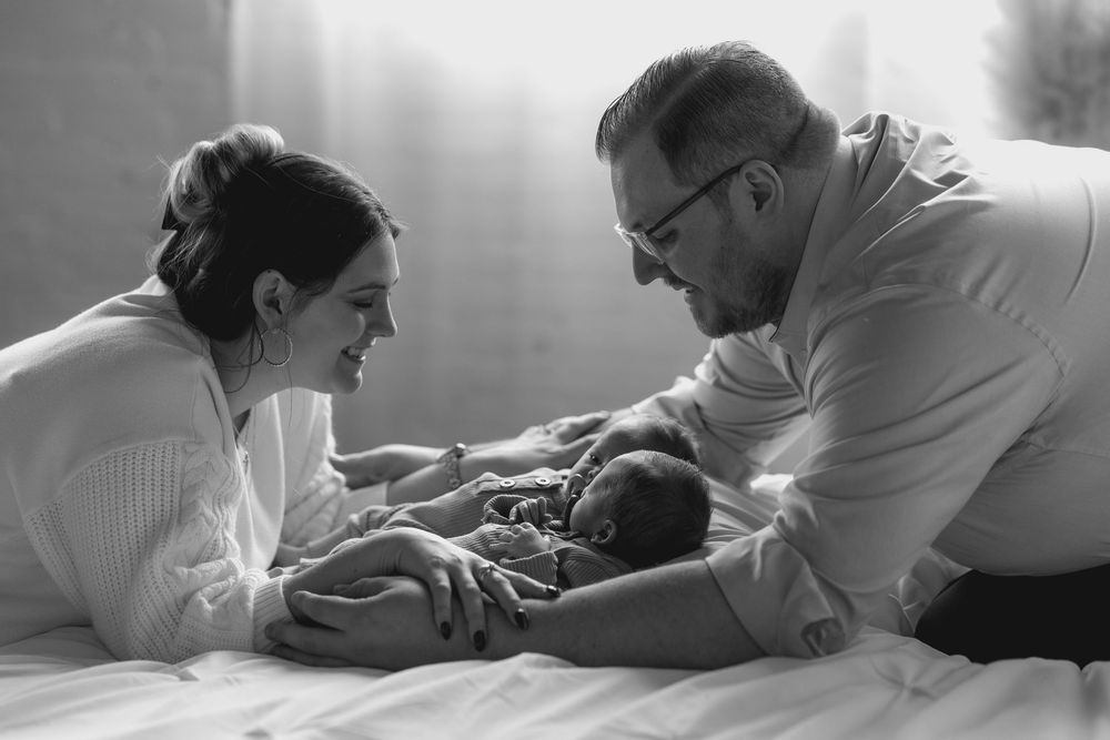 Black and white photo series showing tender moments between two people lying in bed together.