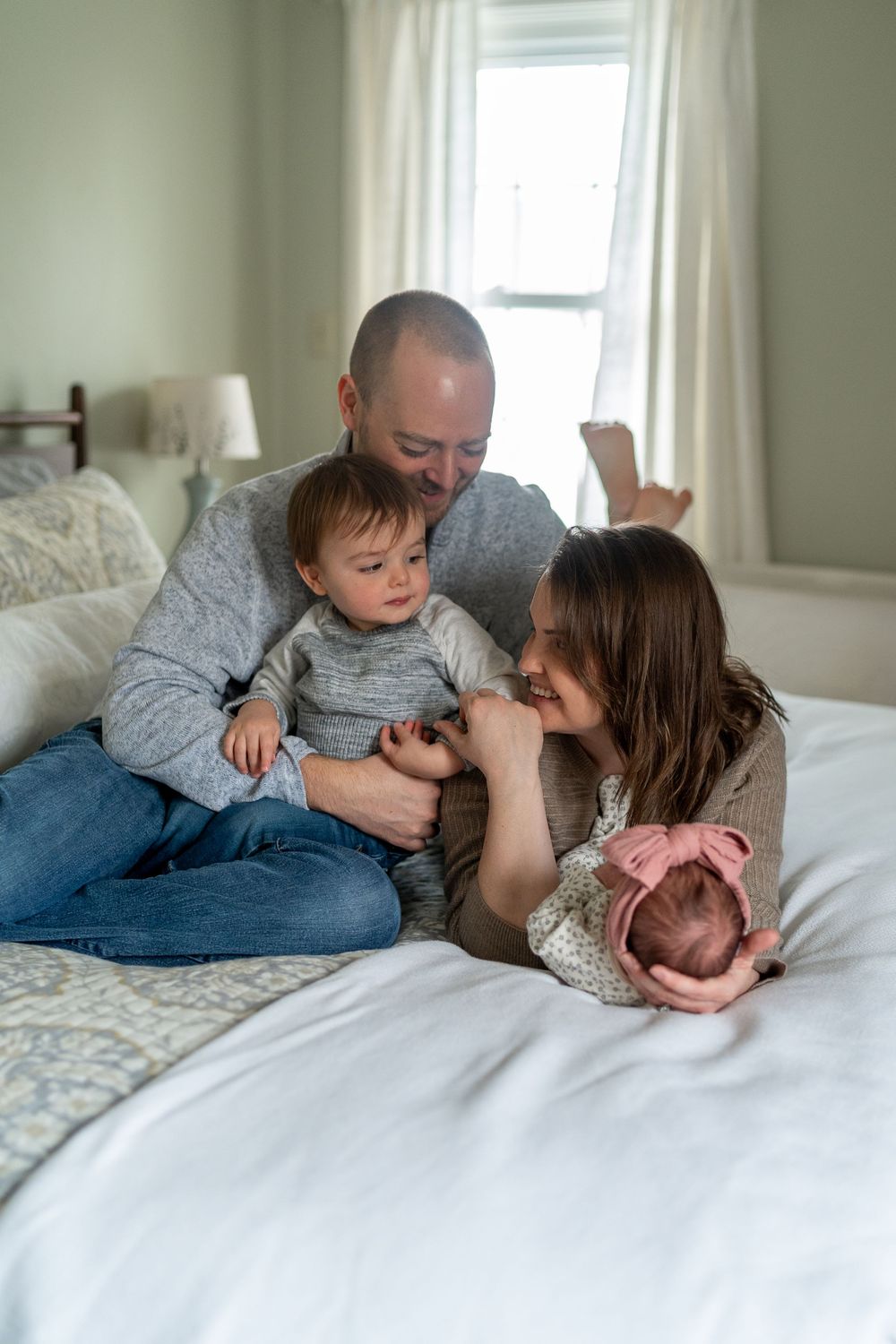 Family members cuddle together on white bedding in a series of candid lifestyle photos showing playful affection.