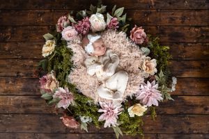 A delicate floral wreath with pink and white roses, moss accents, and lace details on rustic wooden background.