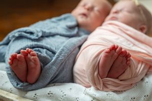 A collage of newborn baby feet wrapped in pink and blue blankets showing tiny toes and soft fabric textures.