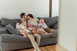 Family relaxing together on a grey sectional sofa at home in a bright white living room.