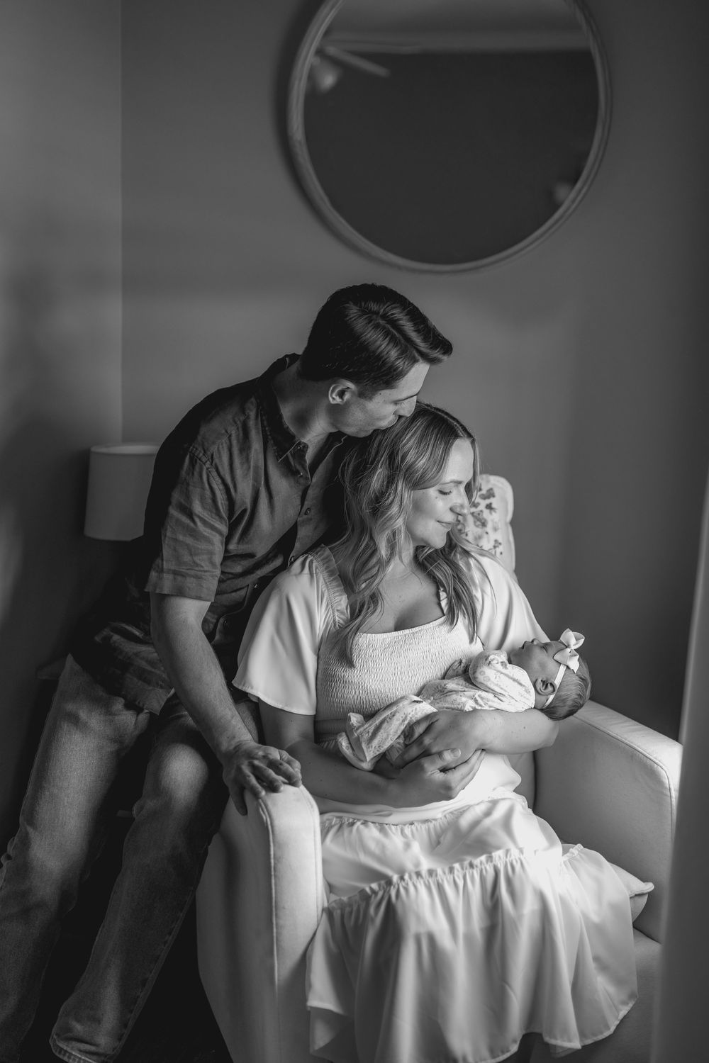 A tender black and white photo series showing intimate moments between a couple and their newborn baby in a hospital room.