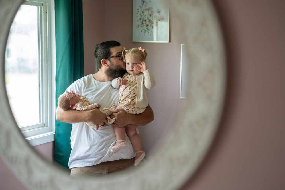A series of four soft, intimate family moments captured through a circular frame against teal walls.