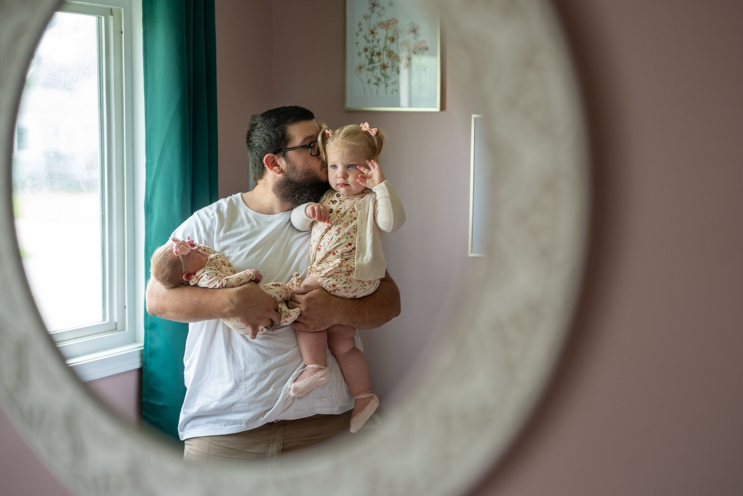 A series of four soft, intimate family moments captured through a circular frame against teal walls.