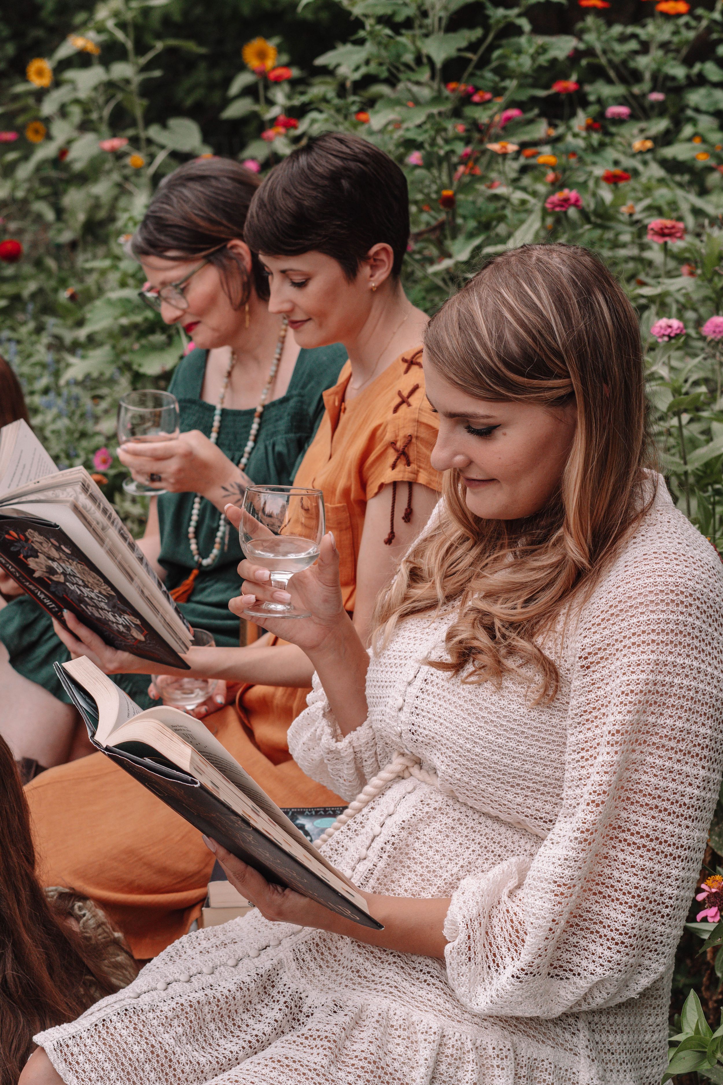 Book club members in white sweaters reading together outdoors.